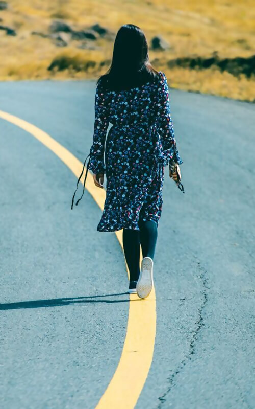 Kvinde vandrer på vejstribe